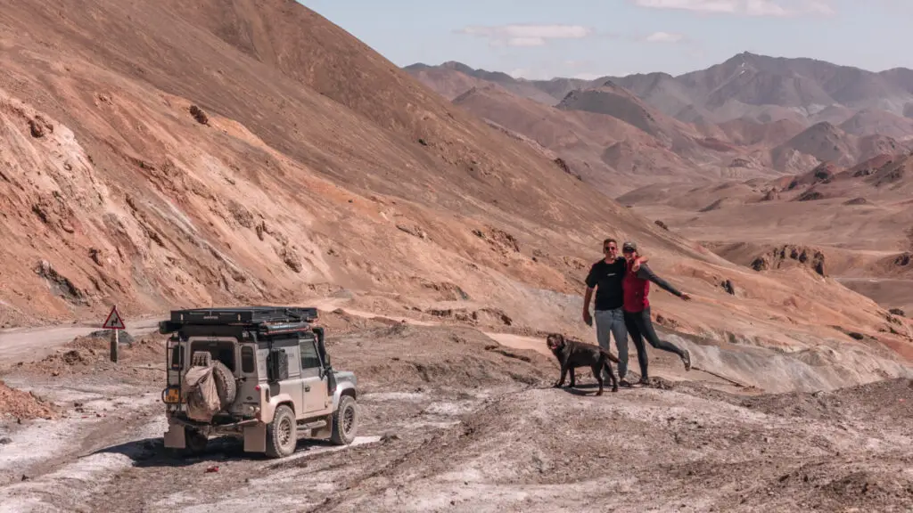 car and couple with dog posing in front of the pamir mountains